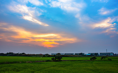 Obraz premium Beautiful light of Sunset with clouds in the sky reflection behind the building and paddy fields.