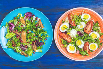 Concept of healthy delicious salads, orange and blue plates, dark wooden table.