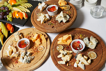 Cheese plate. Assortment of cheese with walnuts, almonds, grapes, figs, strawberries, blueberries and honey on a stone plate