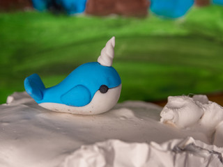 Tiny whale figurine with blurred green background, cute, toy, child, closeup.