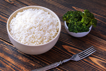 A Cup of white Rice and broccoli on a dark wooden background. Dietary or vegetarian food.