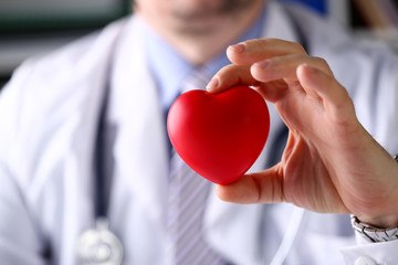 Male medicine doctor hold in arms red toy heart