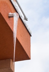 Big icicle hanging on balcony drain. Winter weather specific and life dangerous attention.
