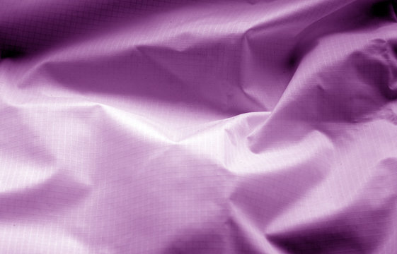 Crumpled transparent plastic surface in purple color.