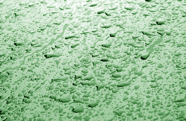 Water drops on car surface in green tone.