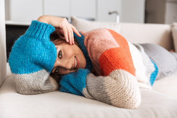 Attractive young woman wearing sweater laying on a couch