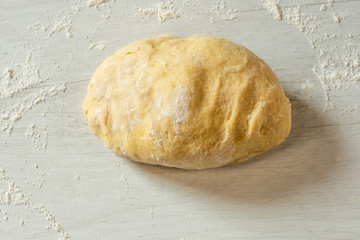 Dough for traditional bread cooking on light wooden background, copy text. Top view, flat.