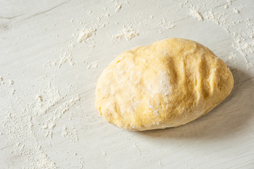 Dough for traditional bread cooking on light wooden background, copy text. Top view, flat.