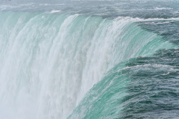An incredible close up view of the top of the famous Niagara waterfall with its clean and cold water falling rapidly and strongly into the precipice