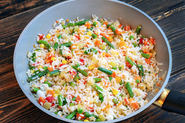 Roasted rice with vegetables in a ceramic pan with a small amount of oil.