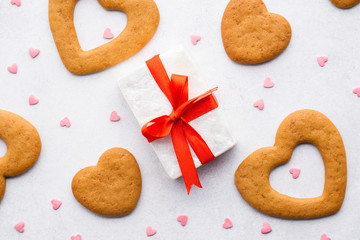 Gift box with red ribbon, heart shaped cookies and candy.