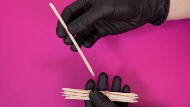 Manicurist handles cuticle with wooden sticks at the beauty salon, women's manicure, healthy nails, nail coating, nail treatment