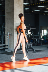 Muscles fit young woman. Fitness female standing in the gym. Sports body and excellent abdominal. Pink sportswear for sportswoman in gym. Sport fashion