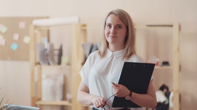 Young girl manager holding clipboard and inviting to working at office