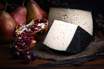 Spanish sheep cheese with grape and other fruit bodegon with classic light on wood