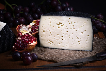 Spanish sheep cheese with grape and other fruit bodegon with classic light on wood