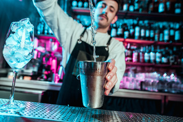 Expert barman is making cocktail at night club or bar. Glass of fiery cocktail on the bar counter against the background of bartenders hands with fire. Barman day concept