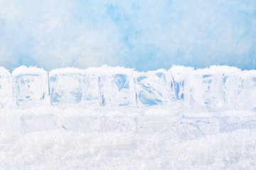 Ice cubes with snow over blue background. Copy space for text or design element.