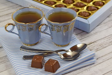 Fresh flavored tea and chocolates on wooden background.
