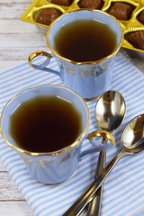 Fresh flavored tea and chocolates on wooden background.