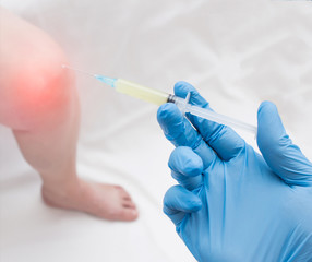 A doctor in medical gloves holds a syringe with plasma to inject a plasma into a patient with a knee that has inflammation, close-up, plasma-lifting