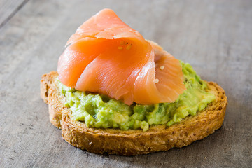 Close up avocado toast with fresh salmon on wooden table