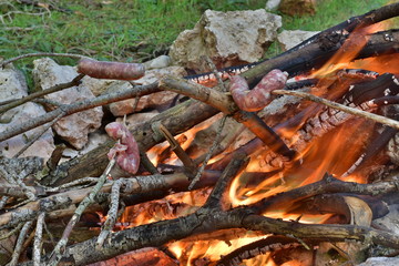 salsiccia a cuocere su di una brace di legna in aperta campagna in sicilia