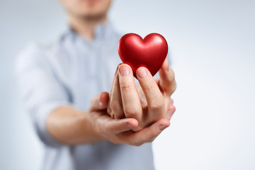 Man holding a red love heart on neutral background