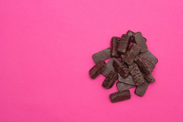 heap of chocolates on pink background, copy space, candy