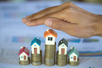 Hand protection, house model on top of stack of money as growth of mortgage credit, Concept of property management. Invesment and Risk Management.