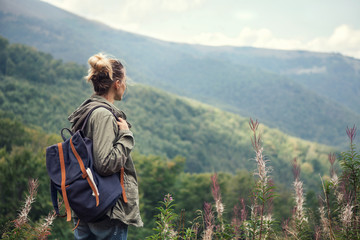 Naklejka na ściany i meble Young woman traveler with backpack hiking in the mountains,