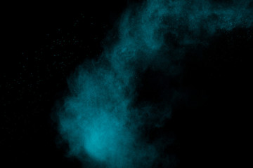 Green blue dust explosion on black background. Freeze motion of color powder splashing.