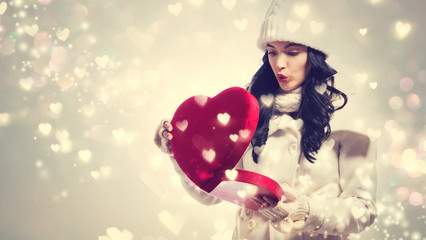 Happy young woman holding a big heart gift box