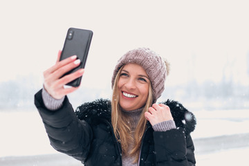 Smiling woman taking selfie outdoors.