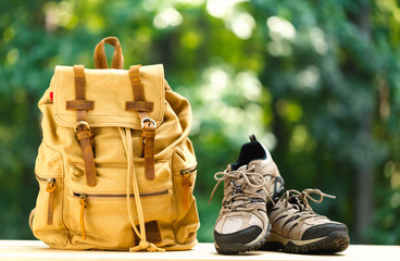 A backpack with hiking boots on a bright summer day in the forest