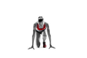 Portrait of young sporty woman at starting block of race isolated over white studio background. The...