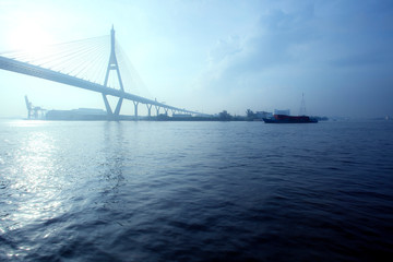 container ship sailing in chaopraya river with bhumibol bridge one of bangkok thailand capital city landmark