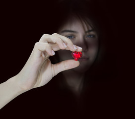 Girl holding heart in hand on black background. Selective focus.
