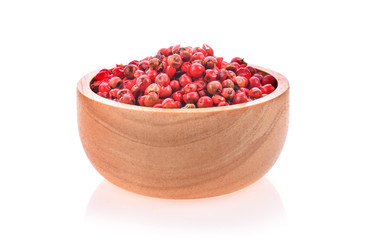 dried pink peppers in wood bowl on white background