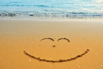 Writing smile on sand beach with blue waves ocean.
