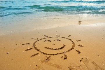 Fototapeta na wymiar Writing sun smile on sand beach with blue waves ocean.