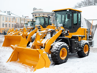 Yellow wheel front loaders. Construction and handling equipment. Heavy diesel tractor, construction machinery, industrial vehicle. Winter time