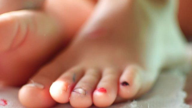 Baby paints her toenails. Close-up.