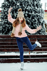 Beautiful girl having fun in winter park, balancing while skating at ice rink. Enjoying nature, winter time