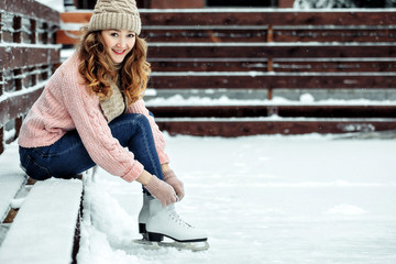 Young woman sitting at skating rink edge in winter