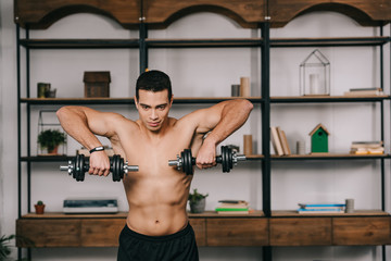 strong bi-racial man exercising with heavy dumbbells