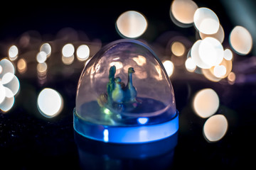 Close up of glass decorative on wooden surface with bokeh background of Christmas lights.