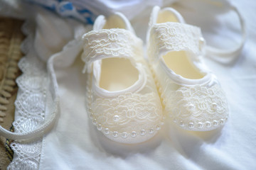 Fototapeta na wymiar Cute baby girl lace and pearls shoes in pair. Horizontal shot of cute accessories for a baby girl, ideas and themes, bride morning preparation.