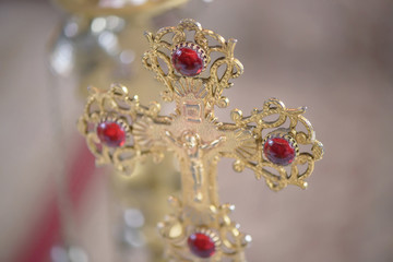 Ornate golden Orthodox cross embellished with red gemstones, a dominant symbol for the Christian faith, in a Romanian church, Brasov, Romania