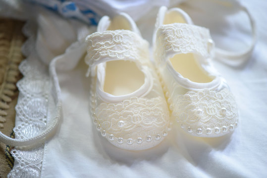 Cute baby girl lace and pearls shoes in pair. Horizontal shot of cute accessories for a baby girl, ideas and themes, bride morning preparation.